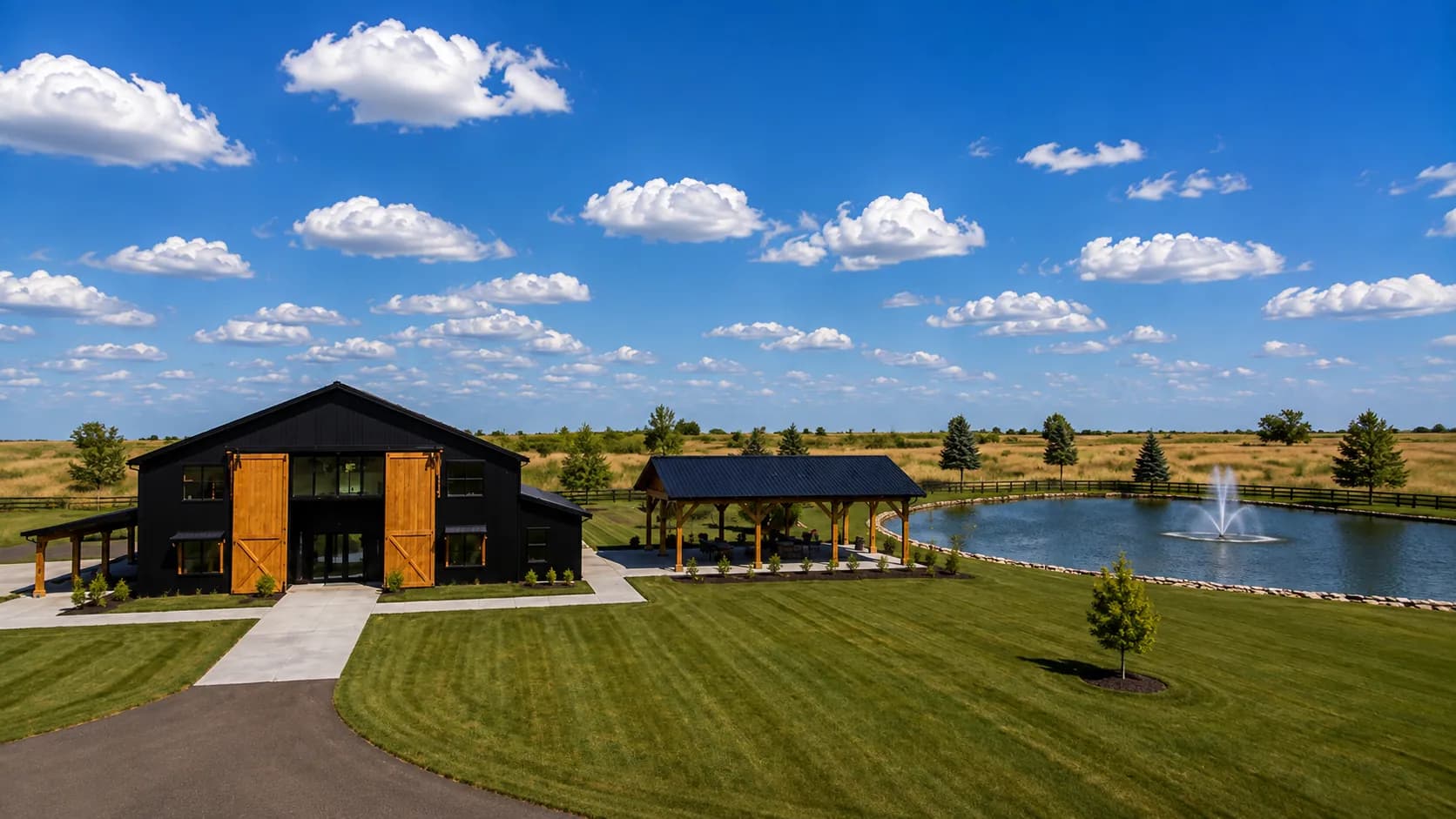 Representación arquitectónica de Antelope Creek Ranch Venue cerca de Wichita, Kansas: un granero para eventos de tablón negro con puertas de cedro, un pabellón techado y una laguna de dos acres con fuente en medio de la pradera abierta.