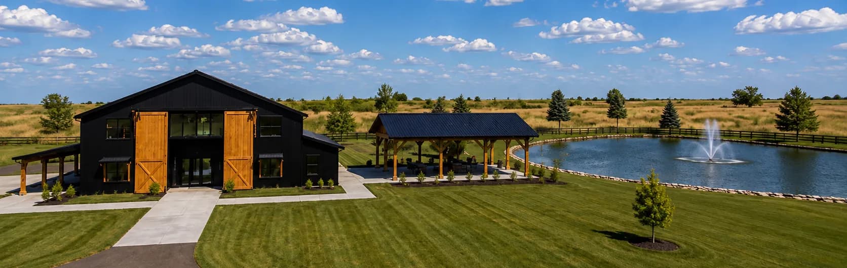 Representación arquitectónica amplia de los terrenos de Antelope Creek Ranch Venue cerca de Wichita, Kansas: el granero, el pabellón techado y la laguna de dos acres sobre la pradera abierta.