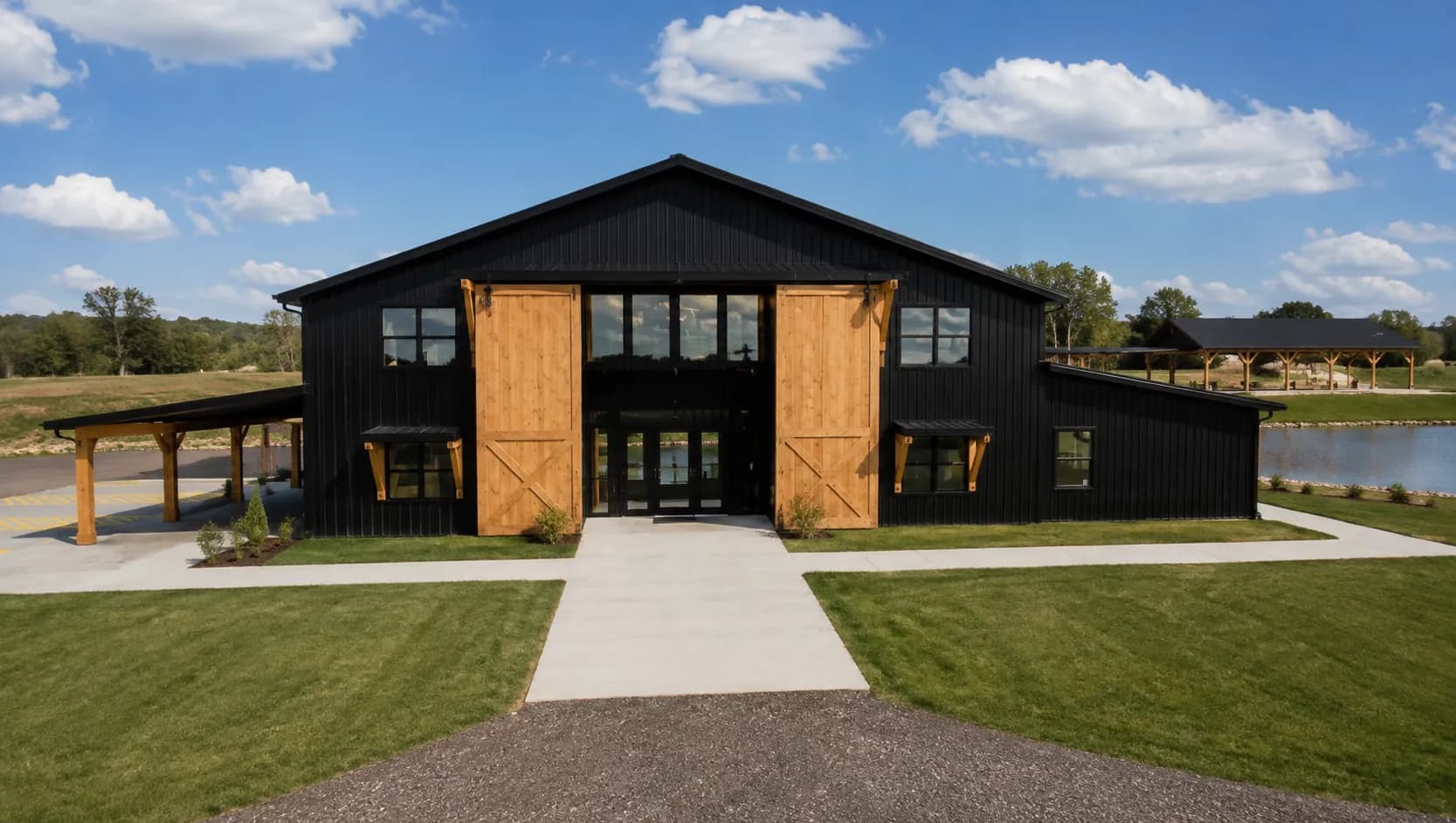 Representación arquitectónica de la fachada de Antelope Creek Ranch Venue cerca de Wichita, Kansas, con puertas de granero de cedro, pórticos techados en ambas alas y la laguna a la derecha.
